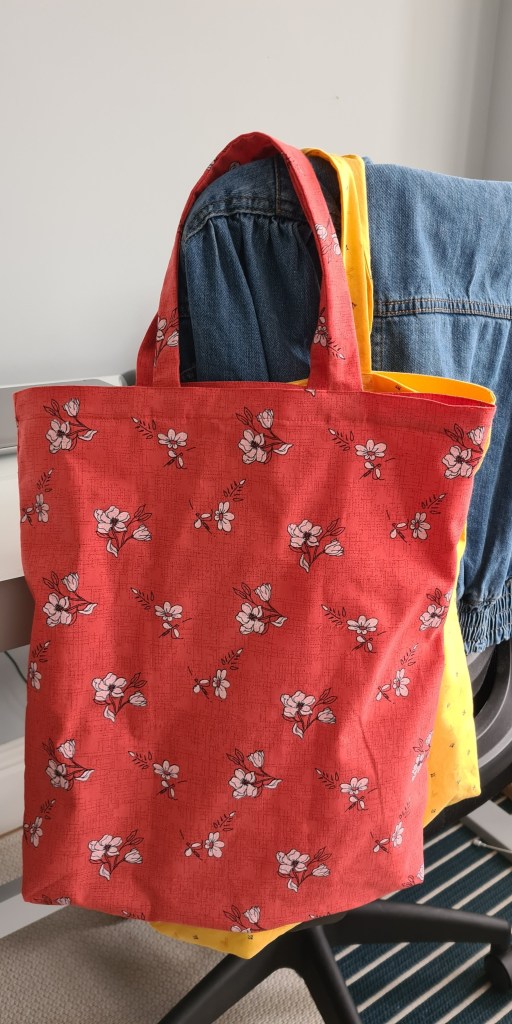 A red hand made tote bag hanging on a chair
