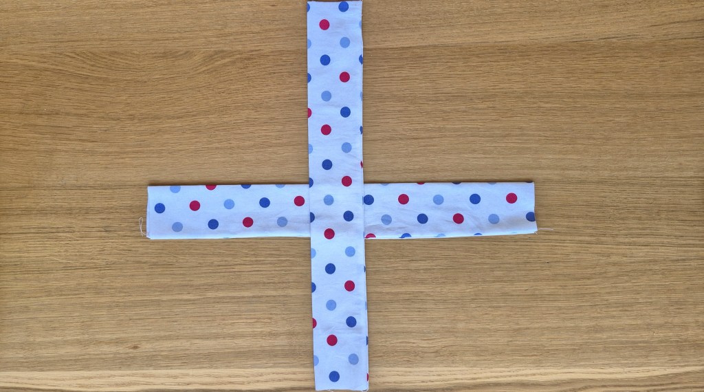 Folding the fabric tube in an X shape to form the twist in the headband.