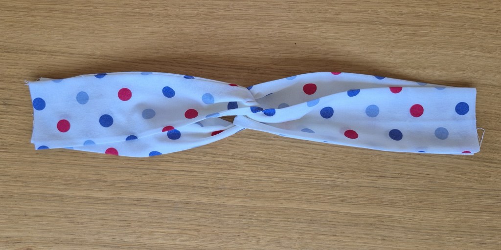 Folding the fabric tube in an X shape to form the twist in the headband.