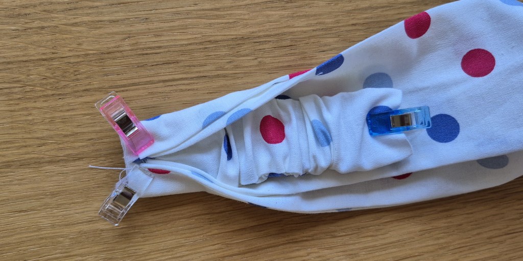 Attaching the elastic casing to the fabric tube to assemble the twisted headband.